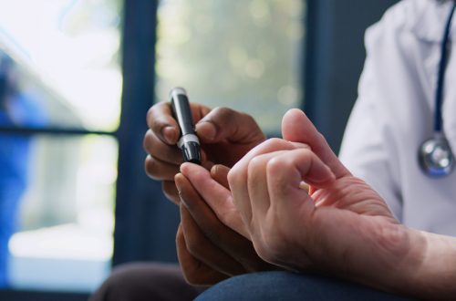 Doctor consulting senior patient Doctor consulting senior patient with glucometer, measuring insulin and glucose level from blood sample. Medic and old man doing diabetic control during checkup visit consultation in hospital lobby.